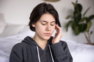 woman eyes closed hand to head